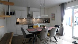 Een moderne keuken met witte kasten, een houten aanrecht en een eethoek met tafel en stoelen.