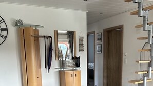 Een moderne woonkamer met een houten vloer, een bank, een houten kast, een spiegel en een trap.