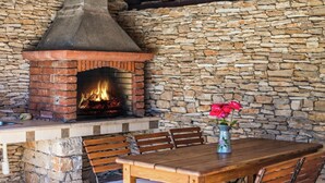 A stone wall with a brick fireplace, wooden table, and chairs. - Authentic Villa With Pool on the Island of Brac, Near the Beach (Supetar)