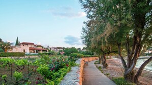 A pathway lined with a stone wall and greenery, leading to a building with multiple windows and a red roof. - Authentic Villa With Pool on the Island of Brac, Near the Beach (Supetar)