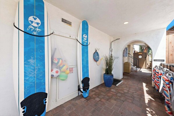 Un pasillo con tablas de surf, una planta y un cartel que indica prohibido el acceso.