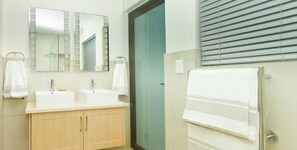 A bathroom with two sinks, a mirror, and a towel rack.