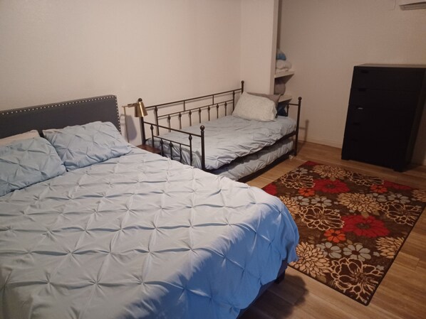 A bedroom with two beds, a wooden floor, and a floral rug.