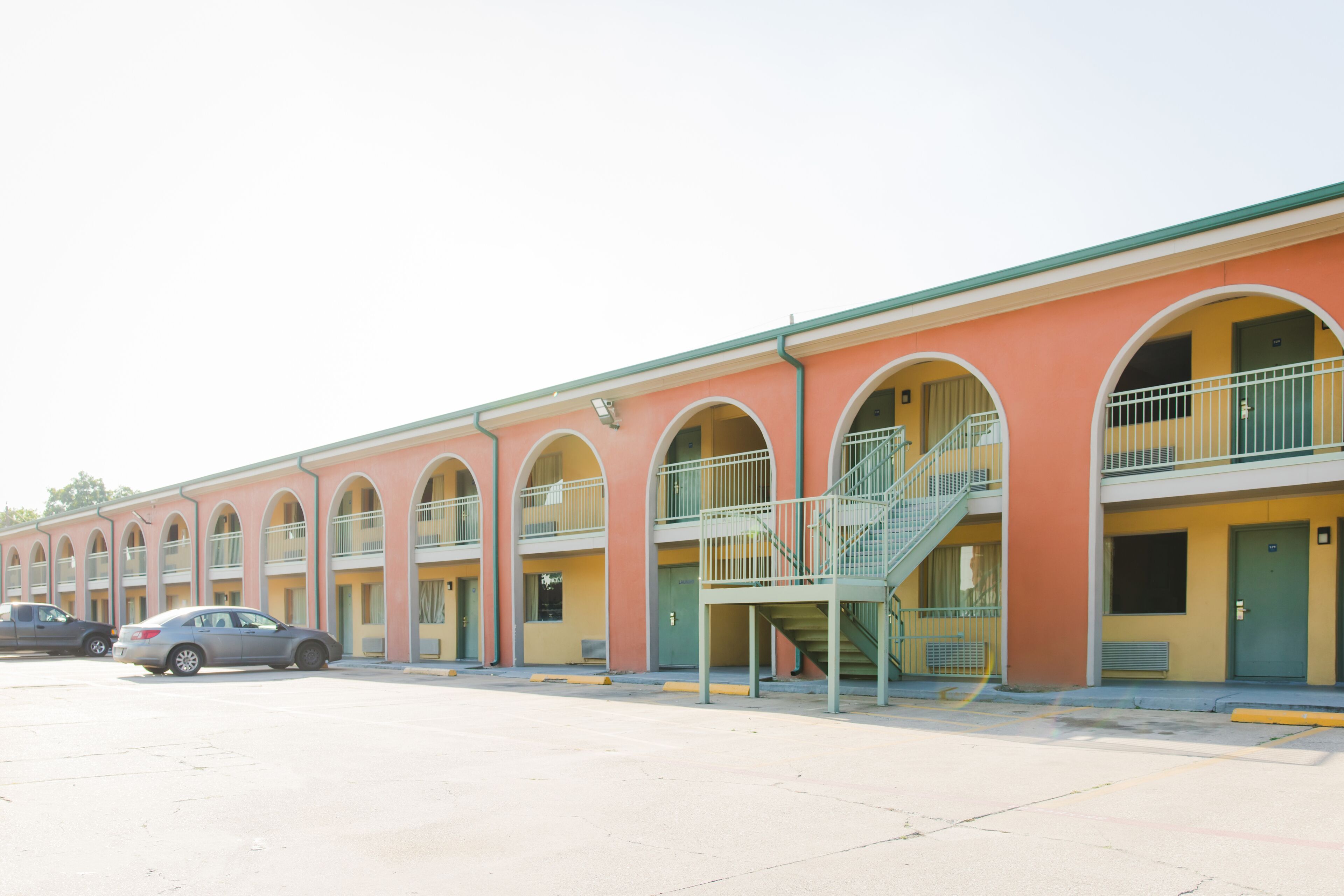 A motel with multiple rooms, each with a balcony and a staircase leading to the upper floor.
