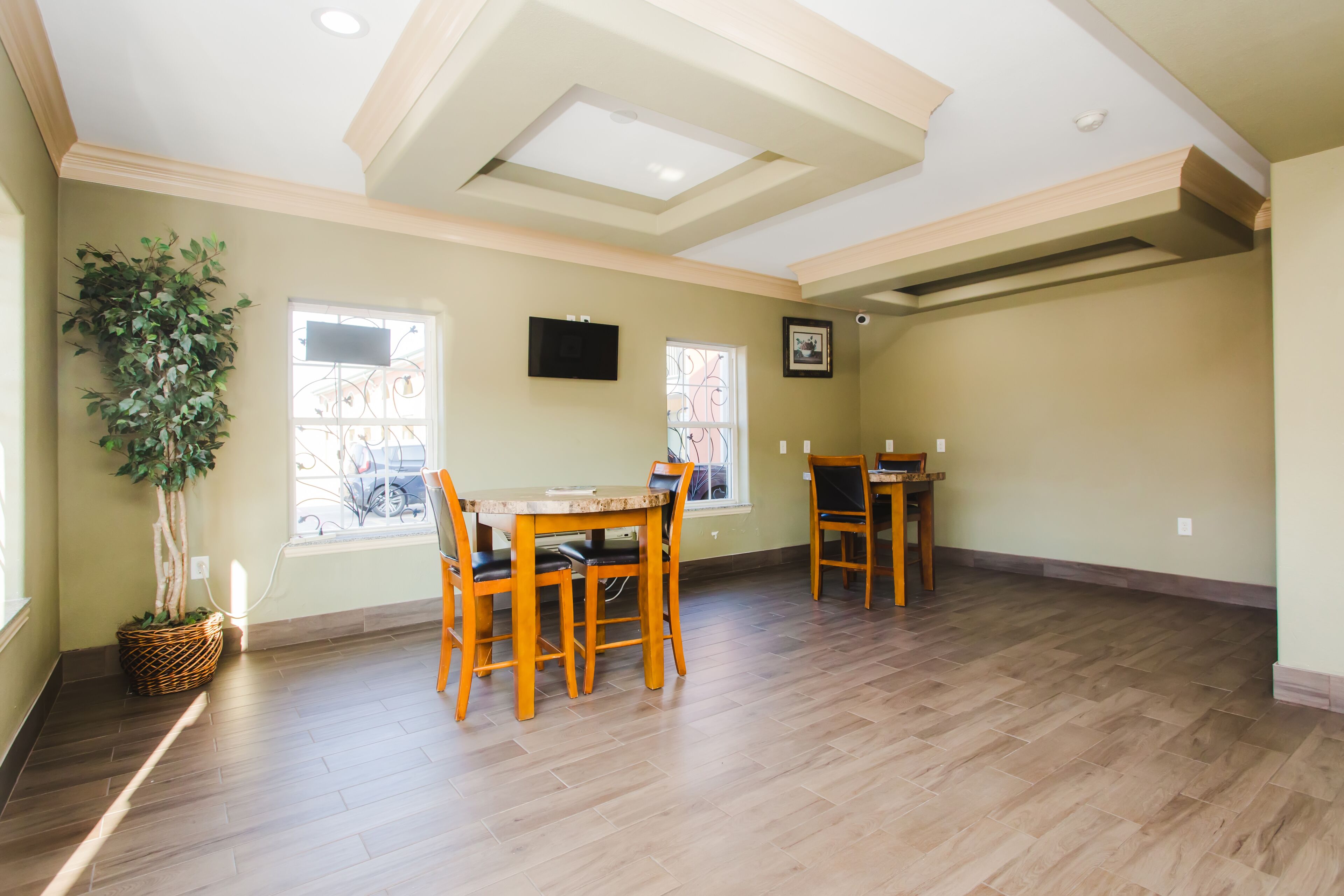 A spacious dining area with wooden furniture and a large potted plant.