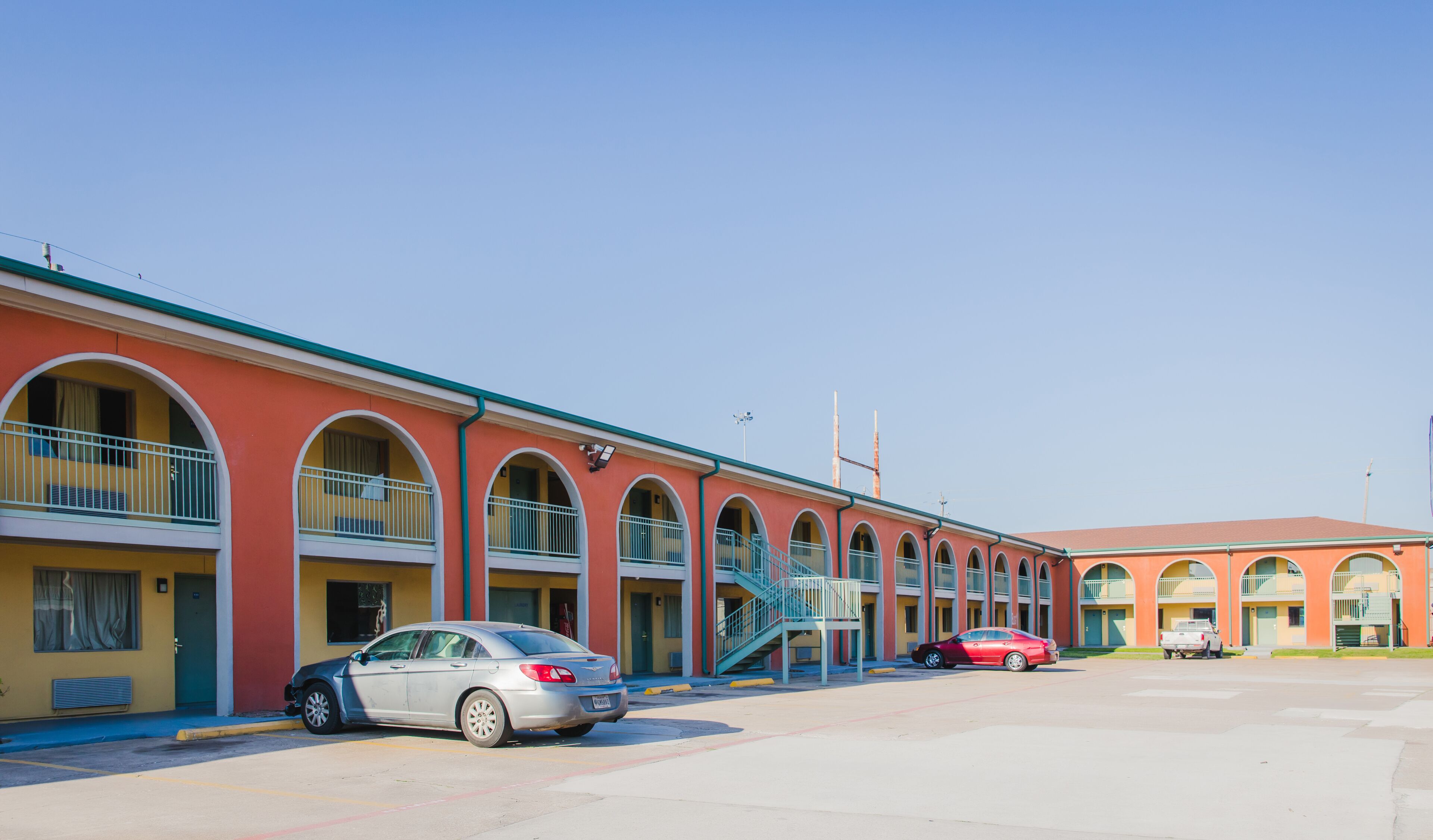 A row of motel buildings with arched windows and a central staircase.