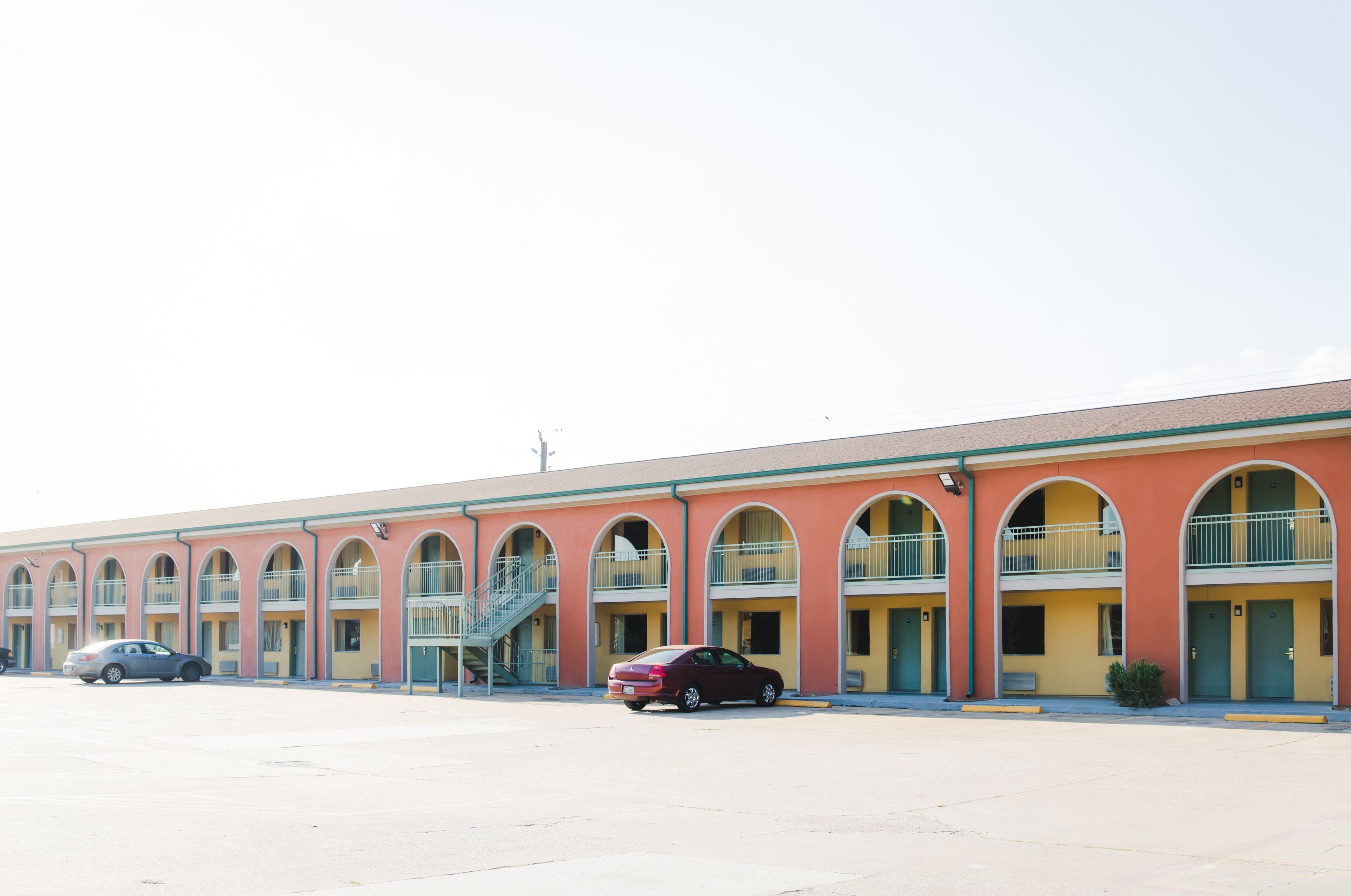 Un motel con varios balcones, un estacionamiento y algunos coches aparcados al frente.