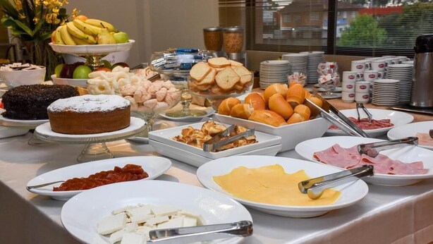 Een buffet met diverse soorten eten, zoals fruit, gebak, kaas en vleeswaren.