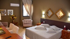 Een hotelkamer met een groot bed, een stoel, een bureau en een nachtkastje.