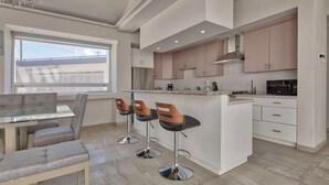 A modern kitchen with a central island, bar stools, and a dining area with a table and chairs. - Gorgeous 3 bed/3bath home in the heart of Ensenada! (Ensenada)