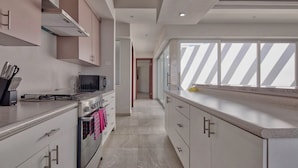 A modern kitchen with stainless steel appliances, a microwave, and a gas stove. There is a window with a view of the sky. - Gorgeous 3 bed/3bath home in the heart of Ensenada! (Ensenada)