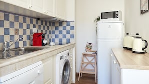 A compact kitchen with a washing machine, a microwave, a coffee maker, and a toaster. - Casa Cosi - Maria Novella (Firenze)
