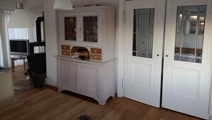 Una habitació amb un armari blanc, una televisió i una porta amb panells de vidre.
