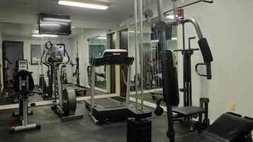 Un gimnasio con equipos de ejercicio variados, incluyendo una caminadora, máquinas de pesas y pesas libres.