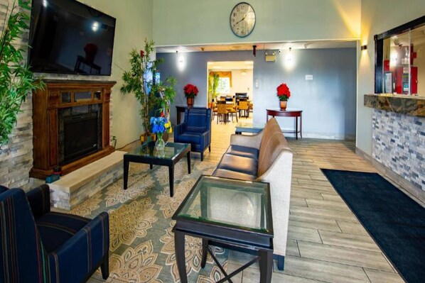 A living room with a fireplace, seating area, and a dining area in the background.