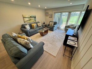 A modern living room with grey sofas, a coffee table, and a TV stand.