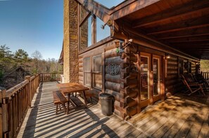 A log cabin with a wooden deck, a table, and chairs. - February Specials! Hot Tub, Cozy Fireplace, 1mile to Pkwy, 2P Arcade Games (Pigeon Forge)