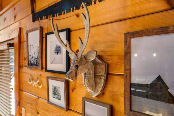 A wooden wall with framed pictures and a mounted deer head. - February Specials! Hot Tub, Cozy Fireplace, 1mile to Pkwy, 2P Arcade Games (Pigeon Forge)