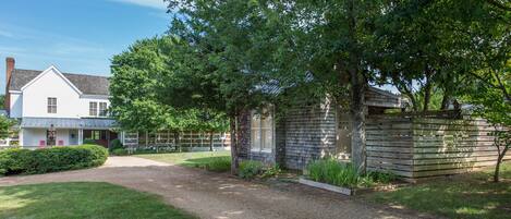 A residential property with a gravel driveway, a wooden fence, and a well-maintained lawn.