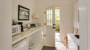 A kitchen with white cabinetry, a microwave, a coffee maker, and a framed picture on the wall.