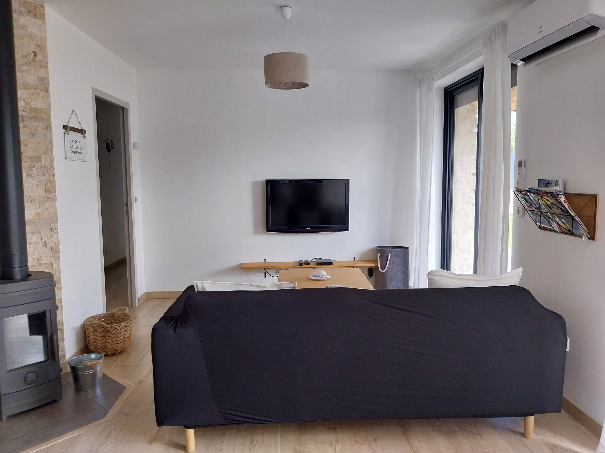 A modern room with a bed, a TV, a fireplace, and a window.