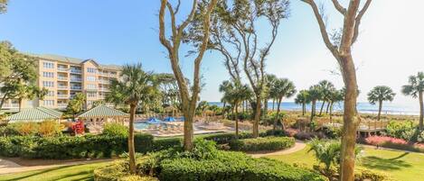 A resort with a pool area, palm trees, and a building with multiple balconies.