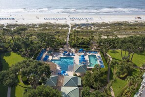 Un complexe hôtelier doté d’une grande piscine, de nombreux transats et offrant une vue sur la plage.