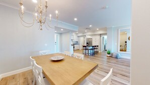 Una cocina moderna con armarios blancos, una mesa de comedor de madera y una lámpara de araña.