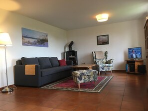 Relax in this inviting living room with a sofa, side table, and ottoman, featuring a fireplace and a mounted TV.