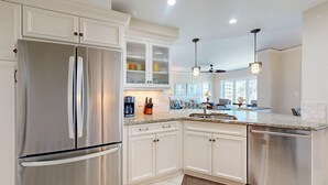 A modern kitchen with white cabinetry, stainless steel appliances, and pendant lighting. - Three Bedroom Oceanfront Property with Views of the Ocean! (Hilton Head)