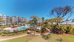 A resort with a swimming pool, palm trees, and a view of the ocean. - Three Bedroom Oceanfront Property with Views of the Ocean! (Hilton Head)