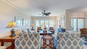 A spacious living room with patterned sofas, a coffee table, and a ceiling fan. - Three Bedroom Oceanfront Property with Views of the Ocean! (Hilton Head)