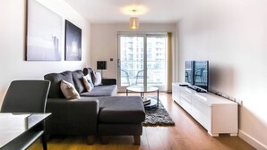En moderne stue med sofa, sofabord, fjernsyn og en bærbar computer.