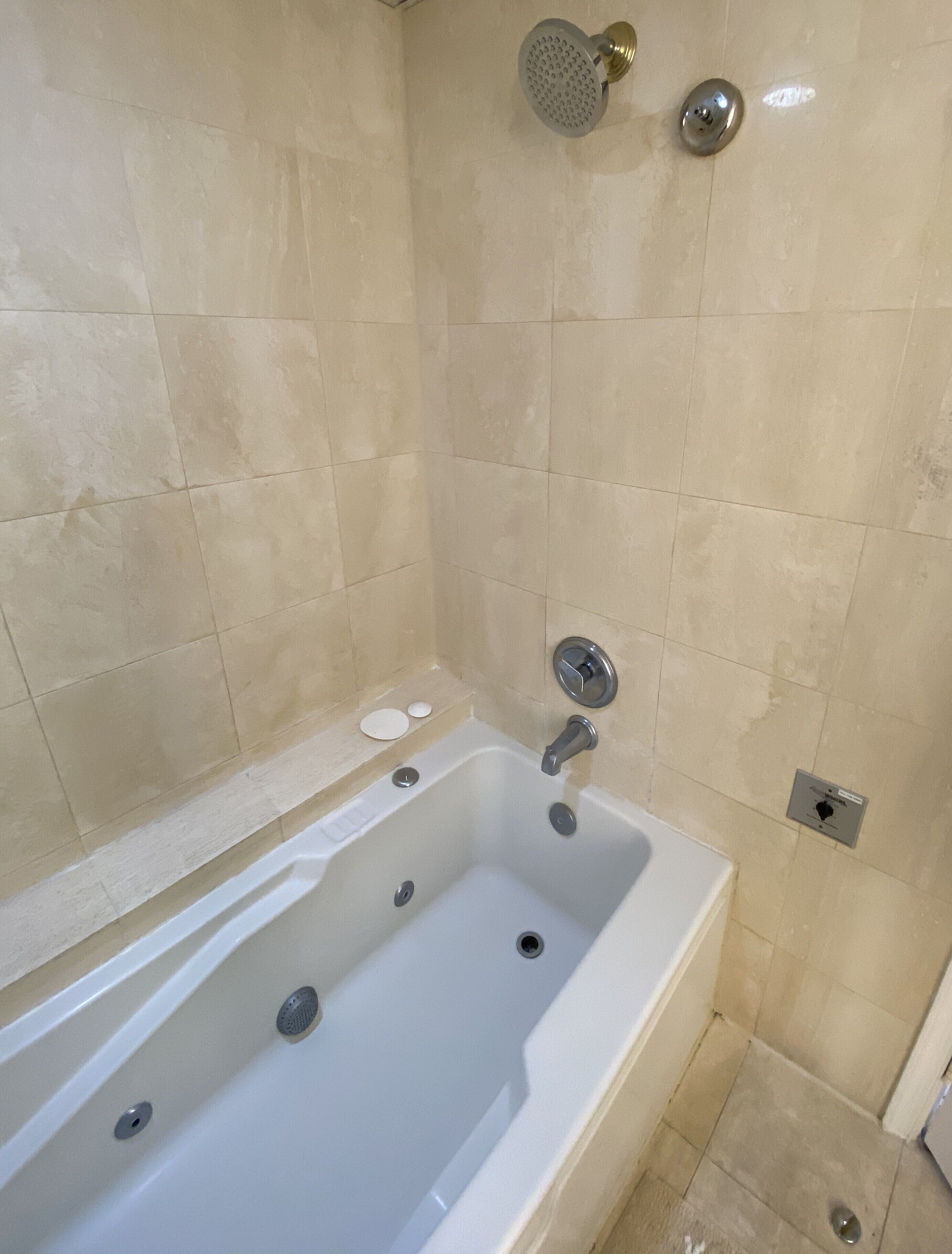 Un baño moderno con una bañera independiente, un cabezal de ducha manual y un grifo de pared.