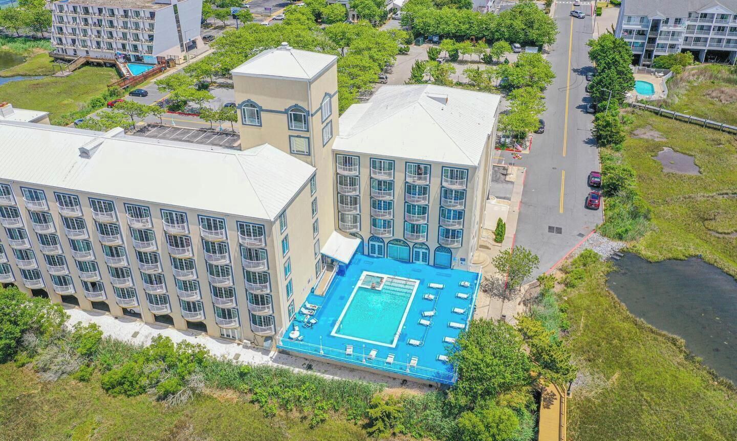 A multi-story hotel with a rooftop pool and a tennis court.