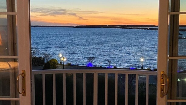 Een open balkon met uitzicht op het water tijdens de zonsondergang.