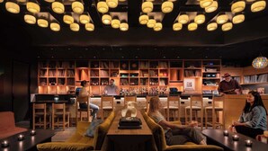 A bar area with multiple seating options, a bar counter, and a bookshelf filled with books and records. - Chic SoCo Studio | Balcony + Walkable Austin (Austin)