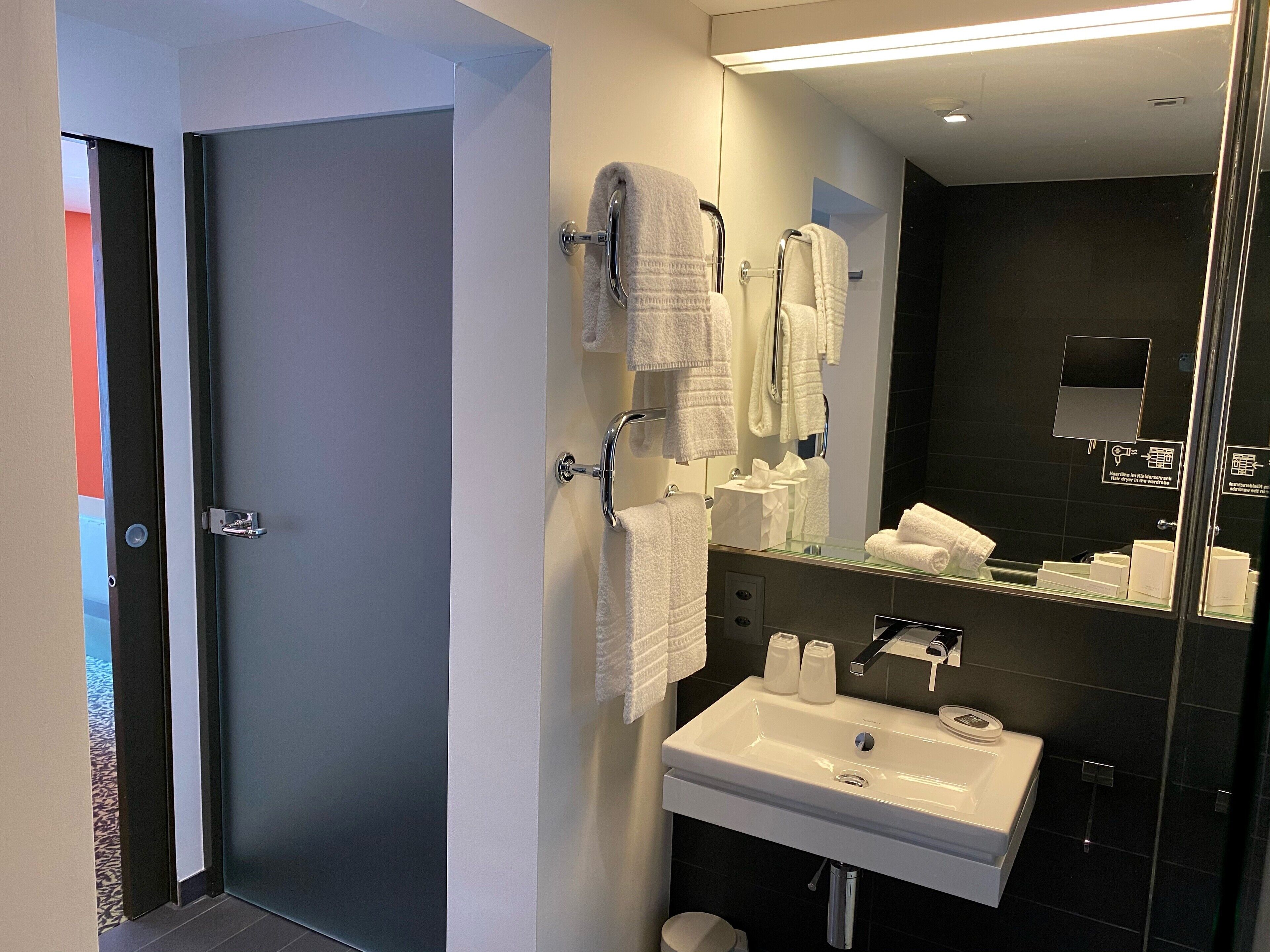 A modern bathroom with a white sink, mirror, and towel rack.
