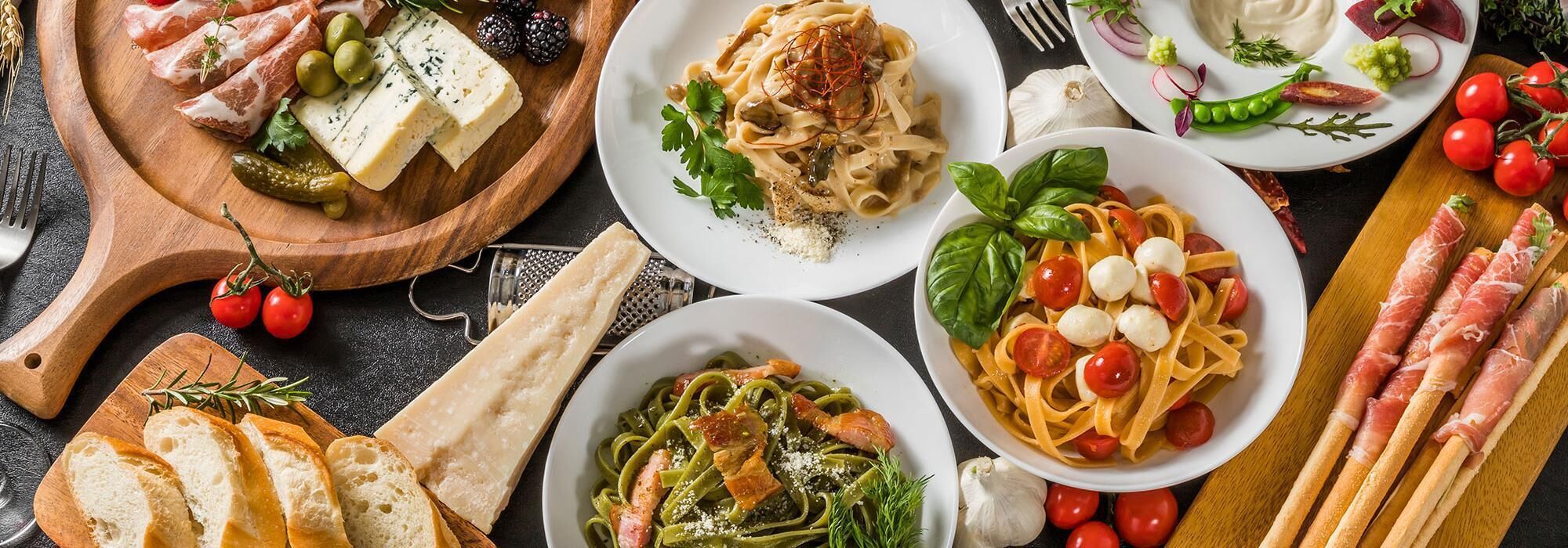 A variety of dishes including pasta, cheese, and meats, suggesting a meal setting.