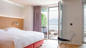 A hotel room with a bed, a chair, and a view of the outdoors.