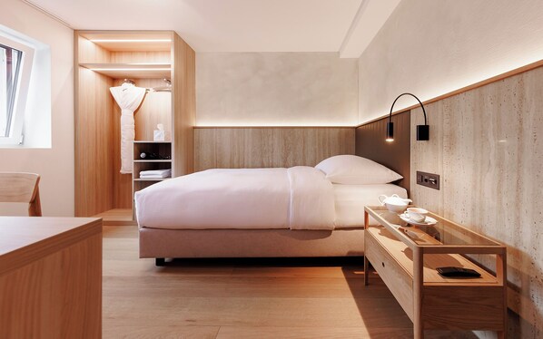 A modern hotel room with a large bed, bedside table, and a small desk with a chair. - Campus Hotel Hertenstein (Weggis)
