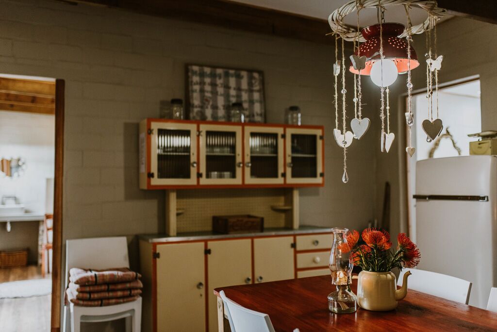 A kitchen with wooden cabinets, a hanging light fixture, and a table with a vase of flowers.