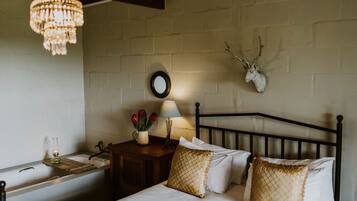 Un dormitorio con cama, mesita de noche, lámpara y una decoración de cabeza de venado en la pared.