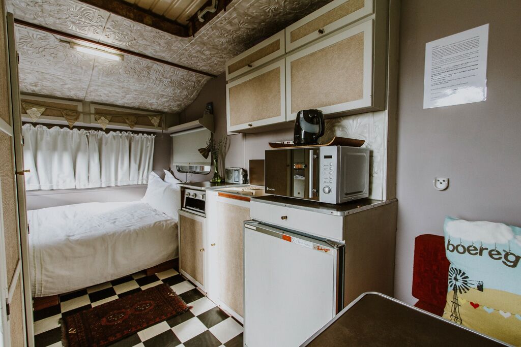 Une petite cuisine équipée comprenant un lit, un four à micro-ondes, un réfrigérateur et une petite table.