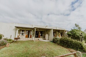 Una casa de una sola planta con porche delantero, base de piedra y un pequeño jardín frontal.