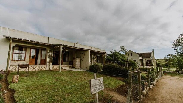 A two-story building with a stone foundation and a flat roof. - The Stables Cottages (Langebaan)