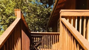 Un escalier en bois mène à une zone abritée, avec une rambarde de chaque côté.