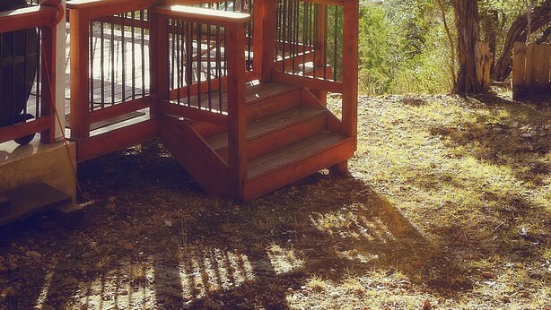 Une terrasse en bois dotée d’une balustrade, qui offre une vue sur un paysage boisé.