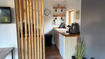 A modern kitchen with wooden slats, a clock, wine glasses, and a coffee maker.