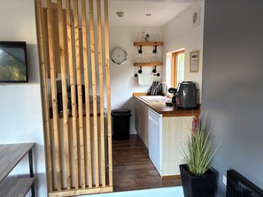 Una cocina moderna con listones de madera, un reloj, copas de vino y una cafetera.